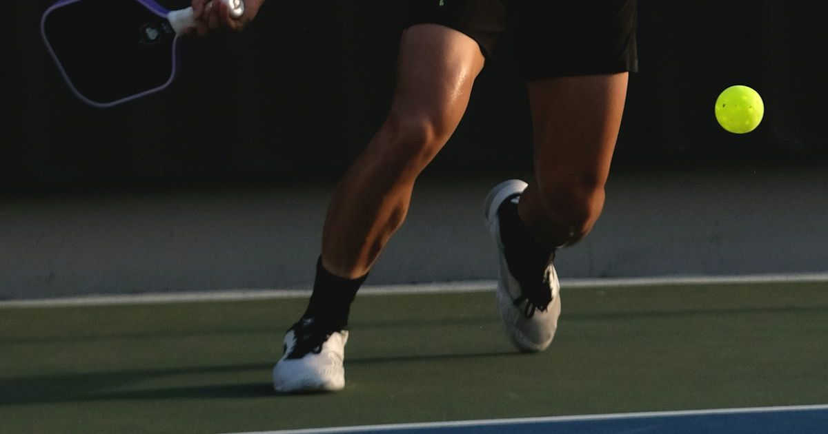 A pickleball player swinging a paddle mid-rally on an outdoor court
