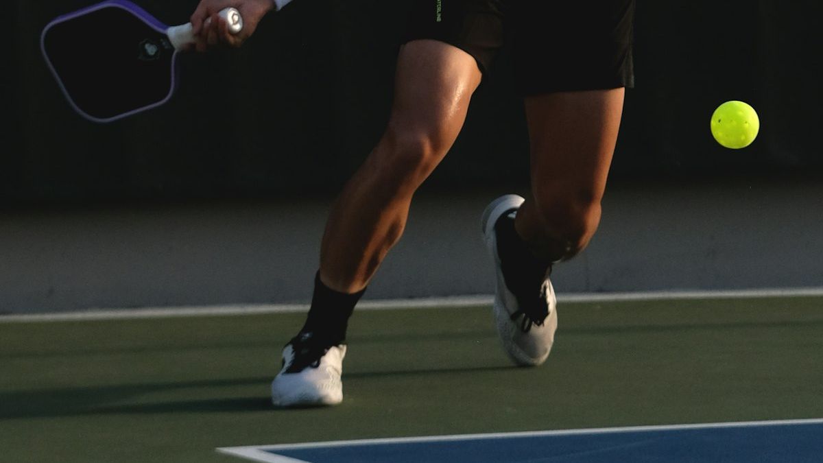 A pickleball player swinging a paddle mid-rally on an outdoor court