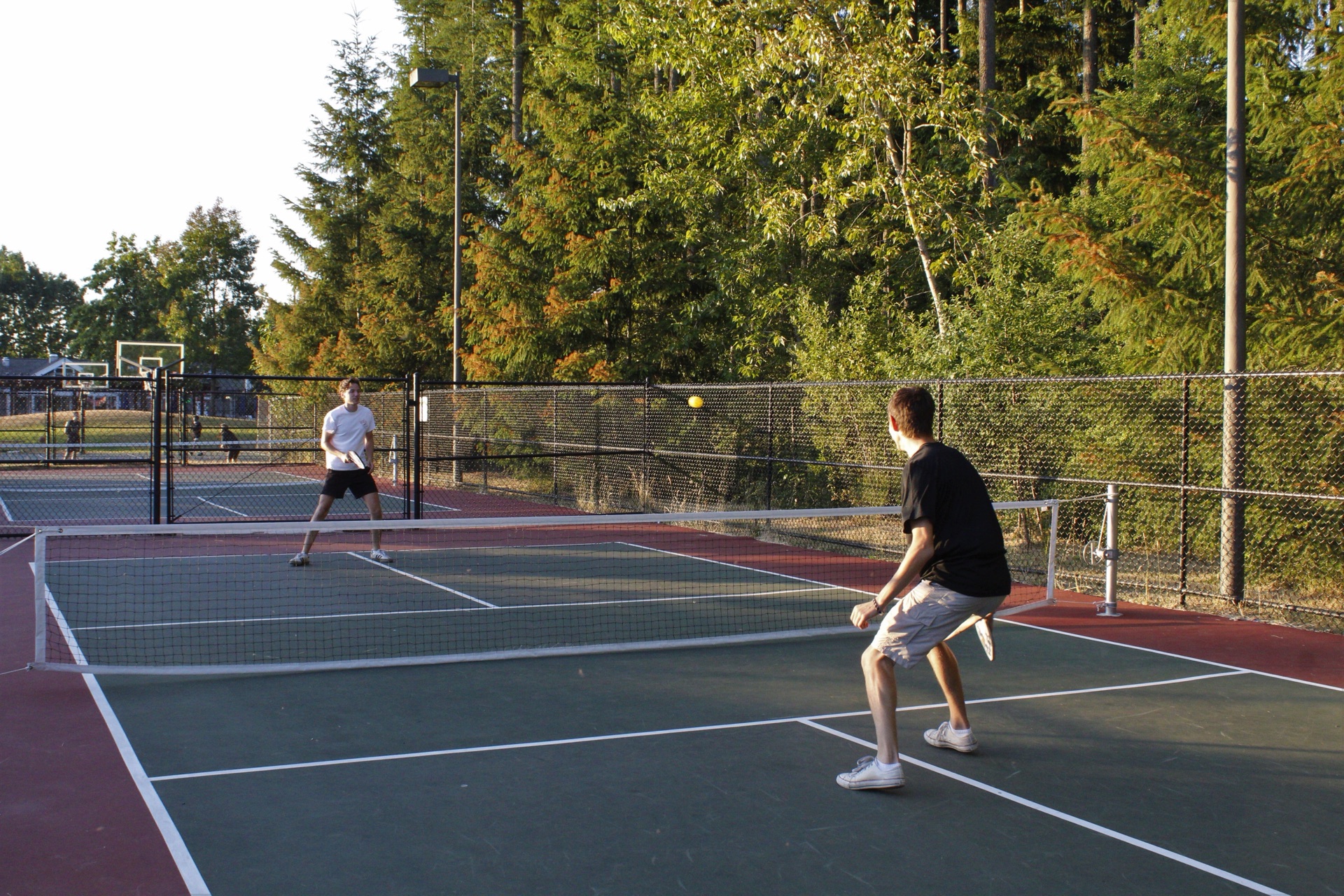 Two players in a rally on an outdoor hard-court pickleball court