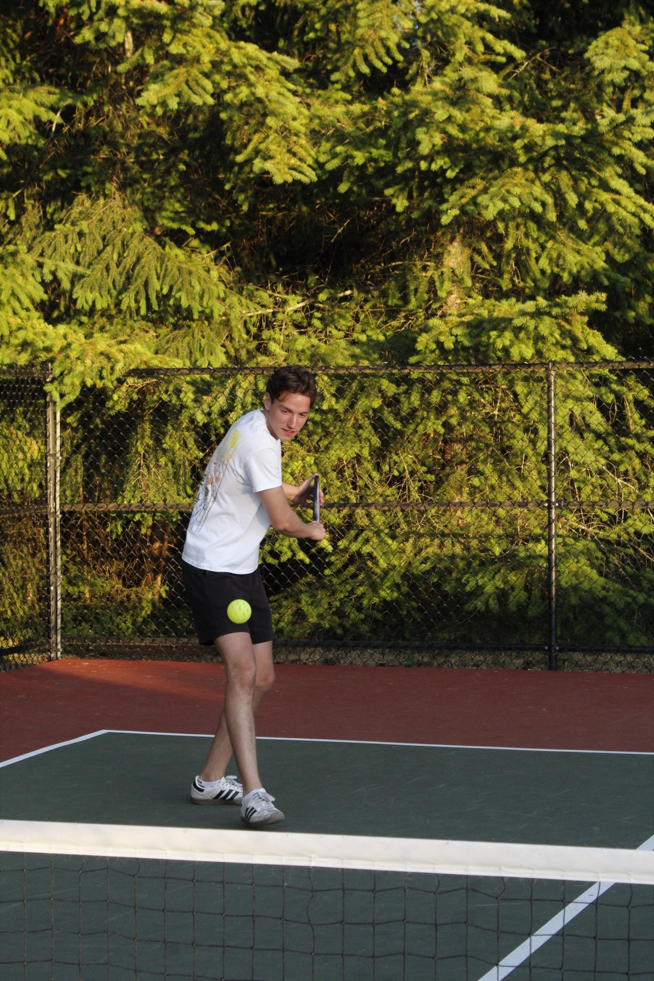 A pickleball player preparing a backhand on an outdoor hard court